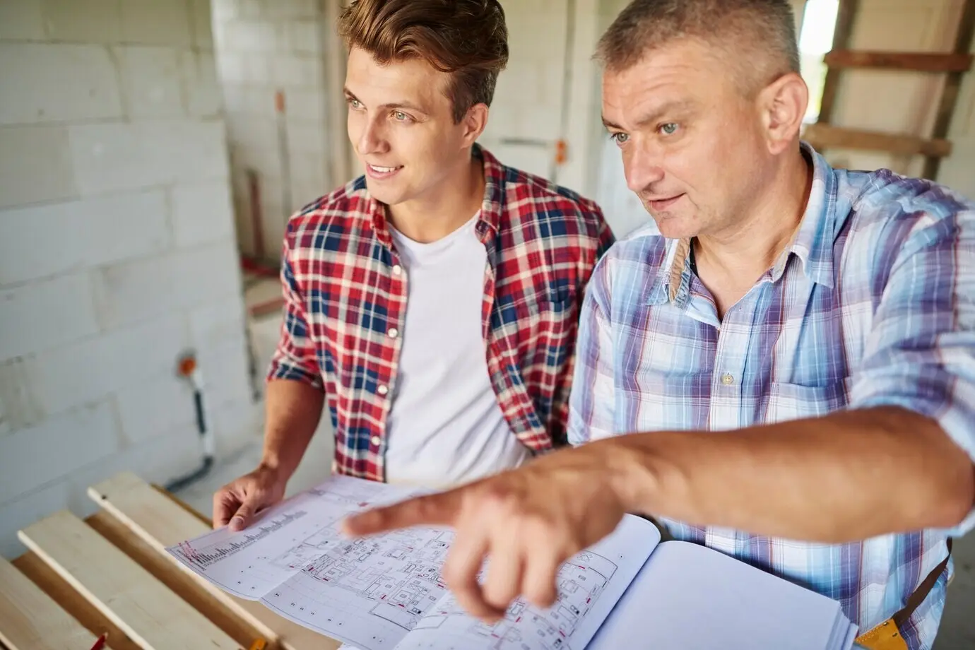 A handsome young carpenter working alongside an experienced man